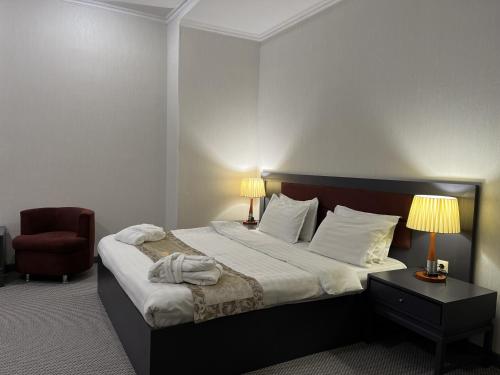 a bedroom with a large bed and a red chair at Almaty Grand Erbil Hotel in Almaty