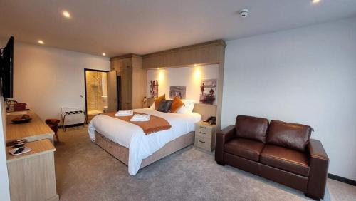 The Teifi Waterside Hotel في كارديغان: غرفة نوم بسرير واريكة جلدية
