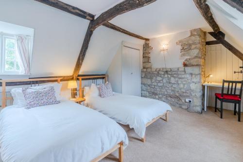 duas camas num quarto com uma parede de pedra em Woodfields em Kineton