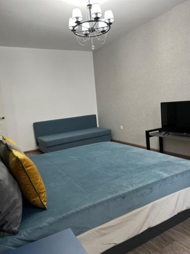 1 dormitorio con cama, sofá y TV en Милая и уютная однокомнатная квартира в г.Тараз, en Taraz