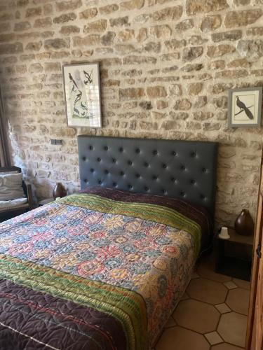 a bedroom with a bed with a brick wall at La Luterne in Villaines-les-Prévôtes