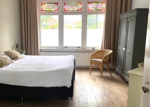 een slaapkamer met een bed, een stoel en een raam bij Next To Sea in Vlissingen