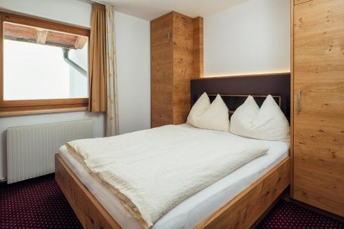 a bedroom with a bed with white sheets and a window at Haus Central in Serfaus