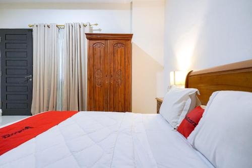 a bedroom with a bed and a wooden cabinet at RedDoorz @ Avros Guest House Medan in Medan