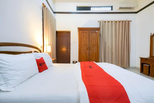 a bedroom with a white bed with red and white pillows at RedDoorz @ Avros Guest House Medan in Medan