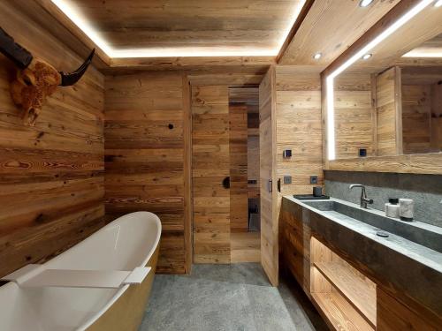 baño con paredes de madera, bañera y lavamanos en Quartz-Montblanc en Chamonix-Mont-Blanc