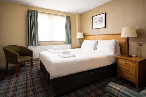 a hotel room with a bed and a chair and a window at The Bamburgh Castle Inn - The Inn Collection Group in Seahouses