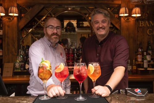 two men standing at a bar with wine glasses at The Bamburgh Castle Inn - The Inn Collection Group in Seahouses