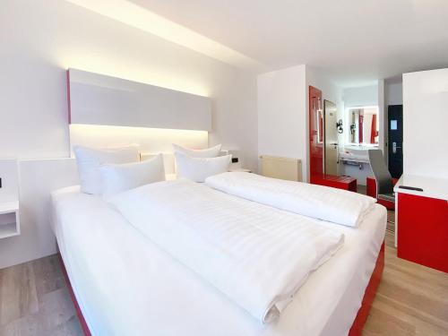 a white bedroom with two beds and a kitchen at DORMERO Hotel Hoyerswerda in Hoyerswerda