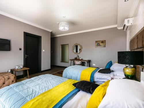 a bedroom with two beds with colorful blankets at Madamz Bed & Breakfast in Gaborone