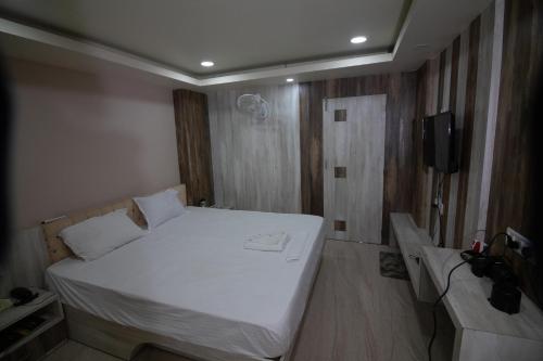 a bedroom with a white bed and a tv at Hotel Himalaya in Agartala