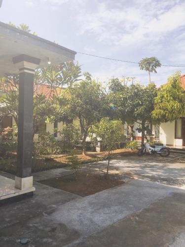 a house with a courtyard with trees and a motorcycle at Kelana Guest House in Lovina