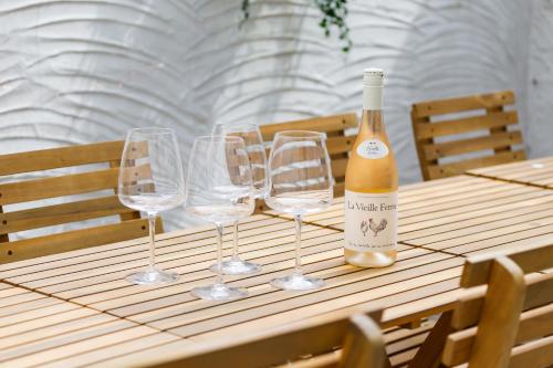 a bottle of wine and four wine glasses on a table at Beachside Retreat 2-Bedroom Gem with FREE Private Parking & Outdoor Space in Brighton & Hove