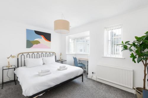 a white bedroom with a bed and a desk at Beachside Retreat 2-Bedroom Gem with FREE Private Parking & Outdoor Space in Brighton & Hove