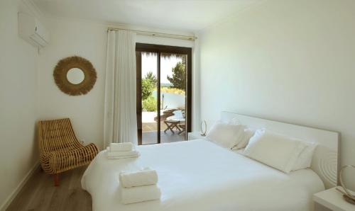 1 dormitorio blanco con 1 cama blanca y 1 silla en The White Villa by The Getaway Collection, en Carvalhal