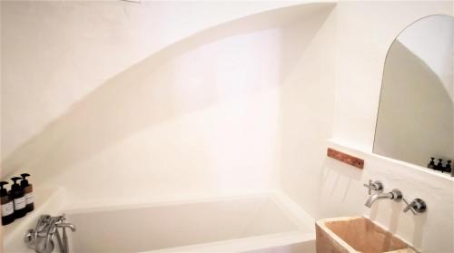 een badkamer met een bad en een wastafel met een spiegel bij Casa El Olmo de Navajas in Navajas