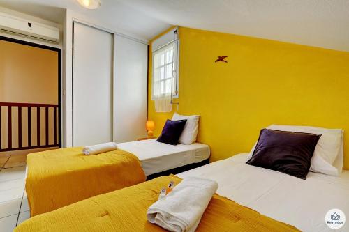 - 2 lits dans une chambre dotée d'un mur jaune dans l'établissement T3 Rustica - Duplex à Saint-Denis, à Sainte-Clotilde
