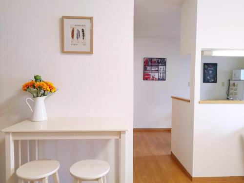 a white table with two stools and a vase with flowers at Hachiken Chaya 2F 1-6ppl in Sapporo