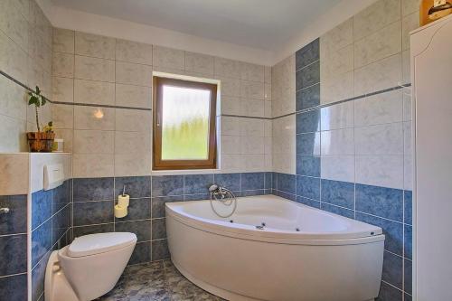 a bathroom with a white tub and a toilet at Villa MAGGIE in Šišan