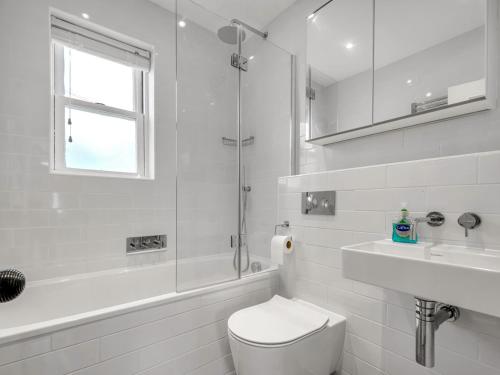 a white bathroom with a toilet and a sink at Pass the Keys Charming cottage in the Heart of Whitstable in Whitstable