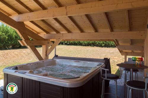 a hot tub under a wooden pergola at Le Val des Sens in Chatte