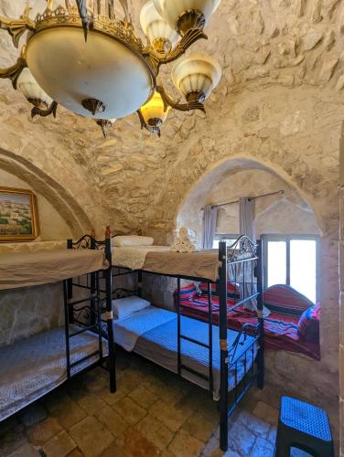 a room with three bunk beds in a stone wall at New Citadel Hostel in Jerusalem