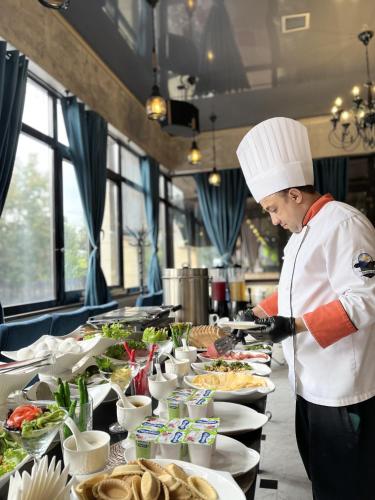 a chef preparing a buffet of food in a restaurant at Almaty Grand Erbil Hotel in Almaty
