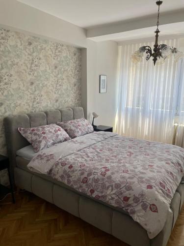 a bedroom with a bed with a flowered blanket and a window at Apartman Filip Lux City Center in Novi Pazar