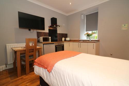 a bedroom with a bed and a kitchen with a television at Signature - Linden Cottage Room 2 in Airdrie