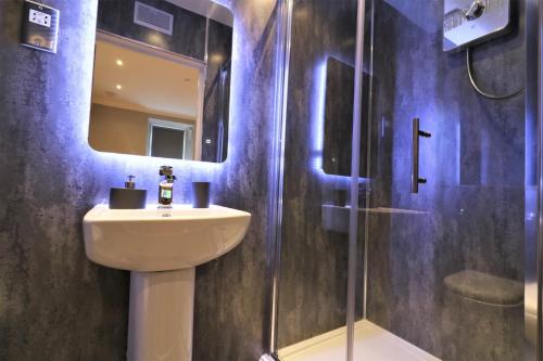 La salle de bains est pourvue d'un lavabo et d'une douche avec un miroir. dans l'établissement Signature - Linden Cottage Room 2, à Airdrie