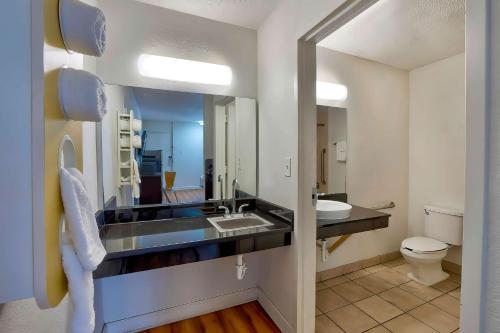 a bathroom with a sink and a toilet and a mirror at Motel 6-Gainesville, FL in Gainesville