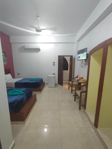 a room with two beds and a table and a television at Nukud guest house in Aswan