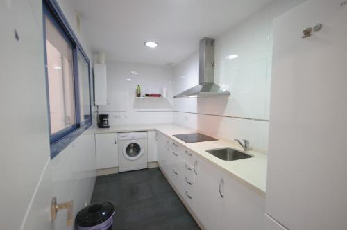 een witte keuken met een wastafel en een wasmachine bij Livingtarifa Sugar in Tarifa