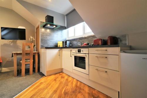 a kitchen with white cabinets and a sink and a table at Signature - Linden Cottage Room 4 in Airdrie
