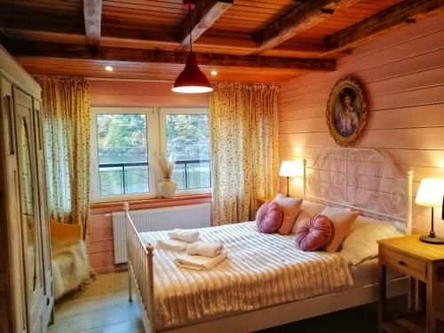 ein Schlafzimmer mit einem Bett in einem Zimmer mit Fenstern in der Unterkunft Słoneczny dom nad Jeziorem Bystrzyckim in Kynau