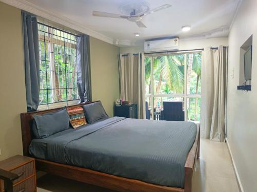 a bedroom with a bed and two large windows at Kanvas Suites - Sun N Moon in Palolem