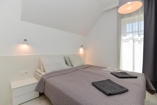 a white bedroom with a bed and a window at Apartment Amber White in Nida