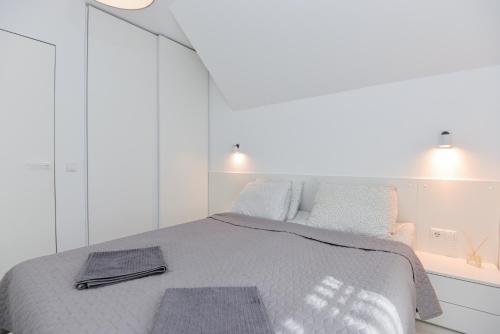 a white bedroom with a bed with two mats on it at Apartment Amber White in Nida