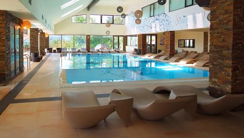 a large swimming pool in a building with chairs at Complex Turistic Creanga Resort & Spa in Tîrgu Ocna
