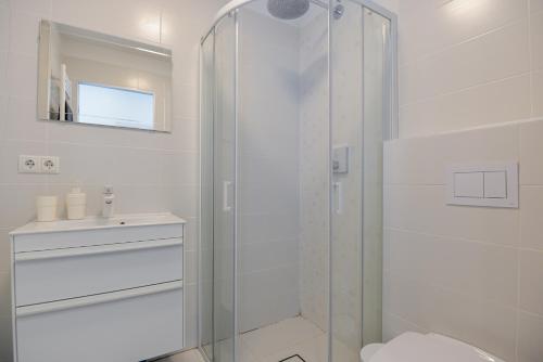 uma casa de banho com um chuveiro, um WC e um lavatório. em Apartment Amber White em Nida
