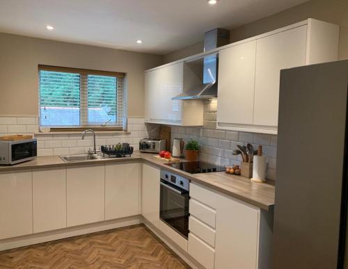 a kitchen with white cabinets and a sink at Apple Tree at Elim Mews in Bowness-on-Windermere
