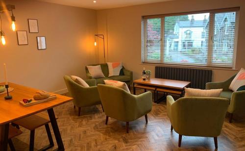una sala de espera con sillas verdes y una mesa en Apple Tree at Elim Mews, en Bowness-on-Windermere