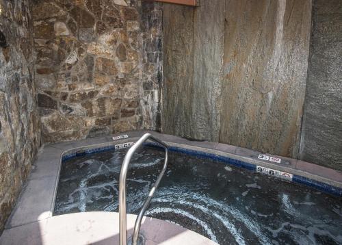 un jacuzzi dans une pièce avec un mur en pierre dans l'établissement Lionsquare Lodge North #294 condo, à Vail