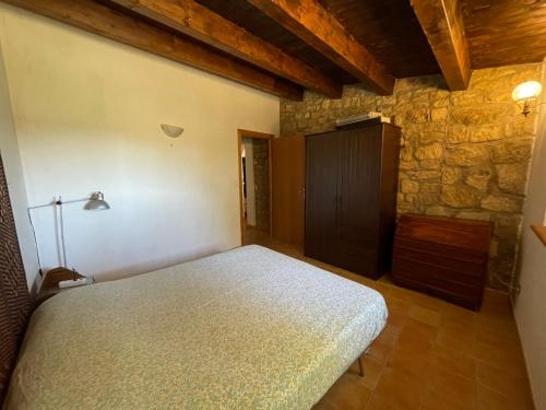 1 dormitorio con cama y pared de piedra en Wonderful house in the heart of Sicily, en Piazza Armerina