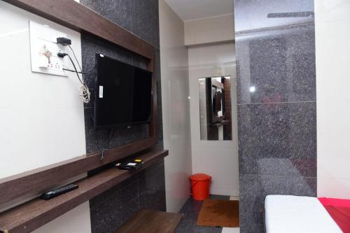 a bathroom with a tv and a shower in a room at Nivant Lodge in Solapur