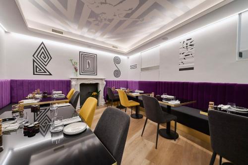 a restaurant with tables and chairs and purple walls at MyTALE Creative Academy Hotel in Rome