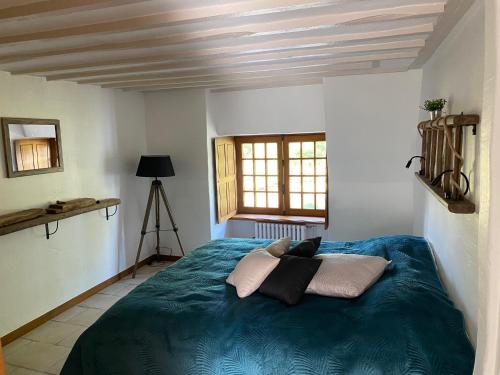 a bedroom with a bed with blue sheets and a window at Moulin d'Ignières in Parcé-sur-Sarthe