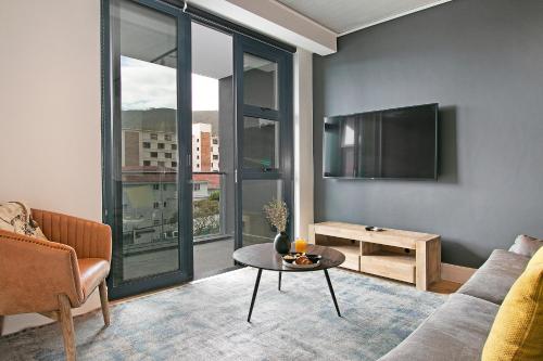 a living room with a couch and a tv and a table at Latitude Aparthotel by Totalstay in Cape Town