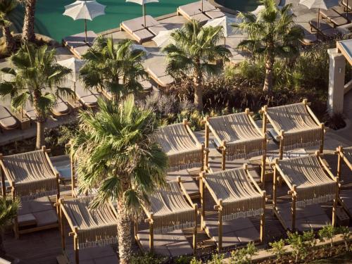 a group of wooden chairs and palm trees at Seaside A Lifestyle Resort - Adults Only in Agia Pelagia