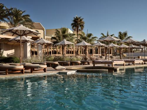 - une piscine avec des tables et des parasols dans l'établissement Seaside A Lifestyle Resort - Adults Only, à Agia Pelagia